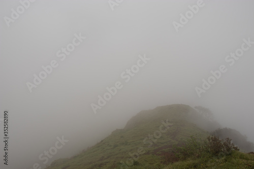 mountain with green grass and thick clouds photo