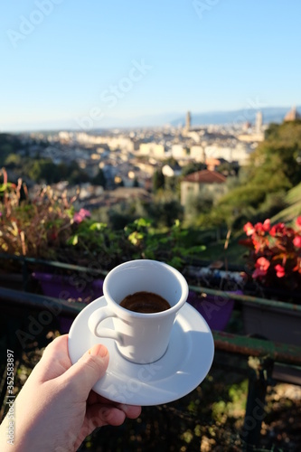 Hand holding espresso cup in front of Florence panorama
