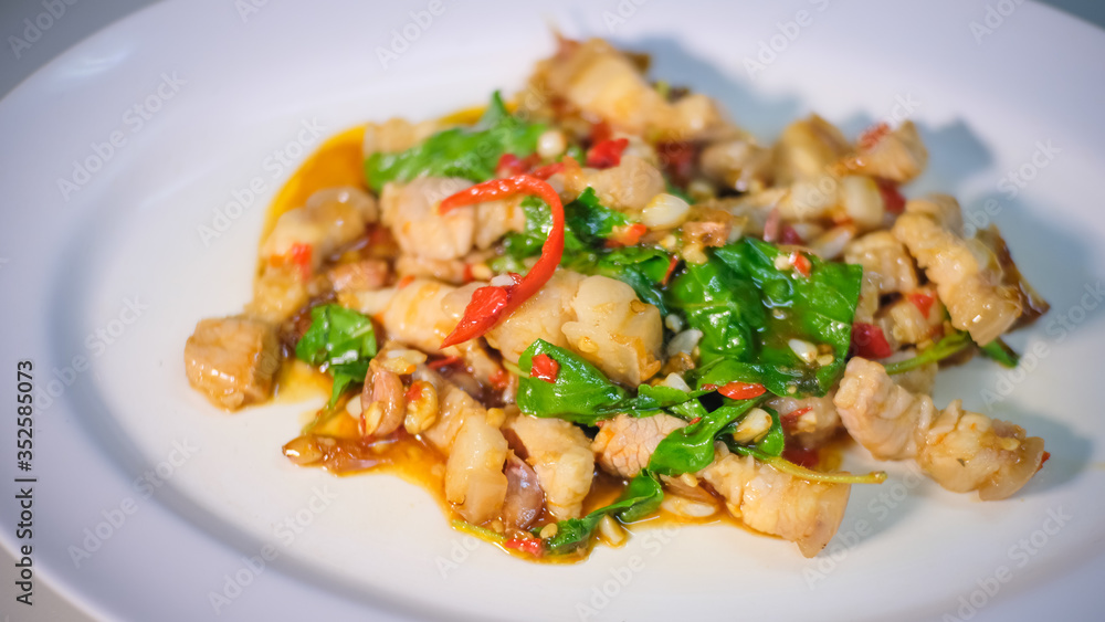 Close up and selective focus of delicious yummy tasty traditional Thai style food hot and spicy stir-fried with pork and basil on white plate , popular food in Thailand. Close up and selective focus of delicious yummy tasty traditional Thai style food hot and spicy stir-fried with pork and basil on white plate , popular food in Thailand.