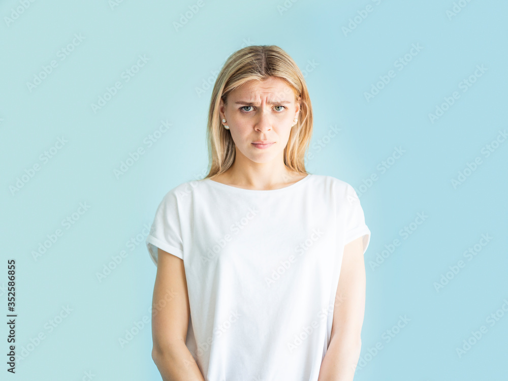 Negative emotion and facial expression. Portrait of angry with frowning face woman looking at you camera isolated blue background Negative emotion and facial expression. Portrait of angry with frowning face woman looking at you camera isolated blue background