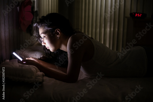 Schilderij op canvas girl with insomnia in quarantine lying in bed looking at the cell phone