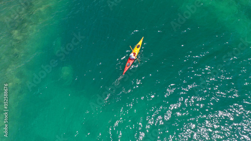 Aerial drone photo of fit athlete rowing with his canoe exploring an exotic destination island