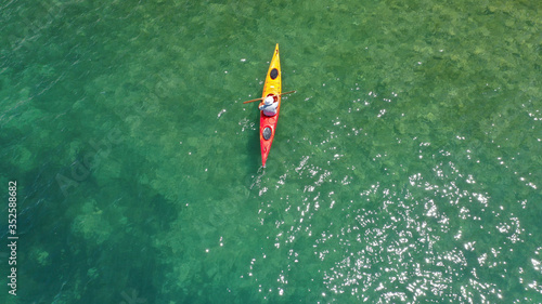 Aerial drone photo of fit athlete rowing with his canoe exploring an exotic destination island © aerial-drone