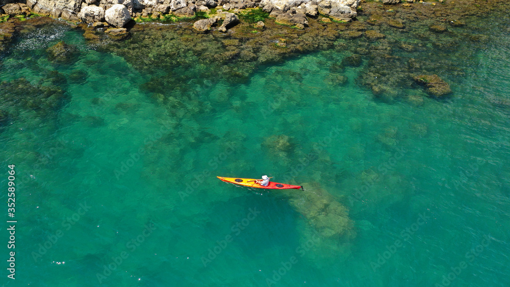Aerial drone photo of fit athlete rowing with his canoe exploring an exotic destination island Aerial drone photo of fit athlete rowing with his canoe exploring an exotic destination island