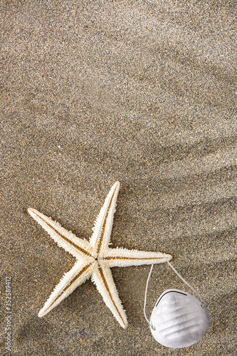 Medical protective mask and starfish on sand