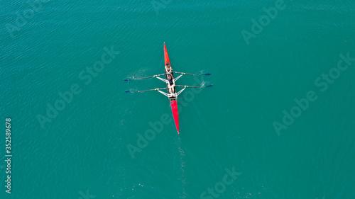 Aerial drone photo of athlete competing in canoe race in tropical lake with emerald waters