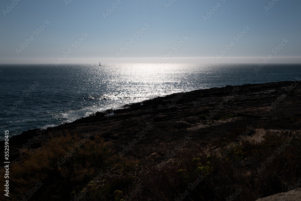 Panorama of the sea with a sailboat against daylight in Caiscas.