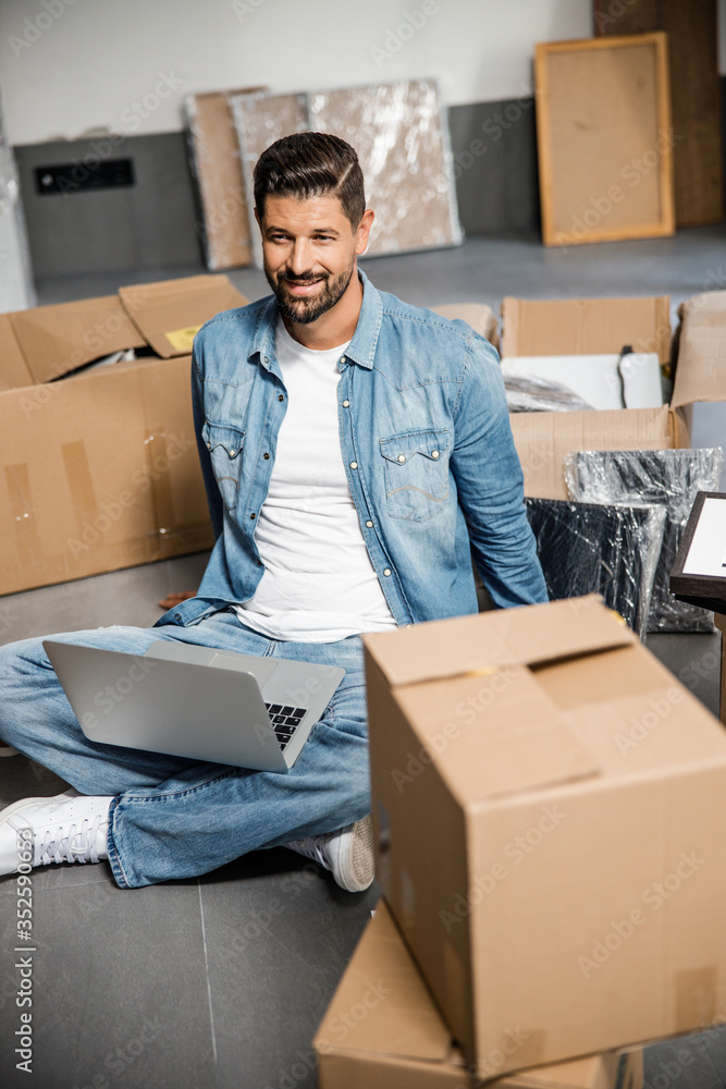 Merry bearded male with notebook near carton boxes Merry bearded male with notebook near carton boxes
