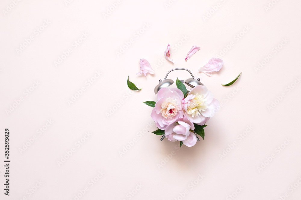 Creative minimalistic composition with a Clock. Alarm clock with peony flowers. Spring time. Time to love. Top view.