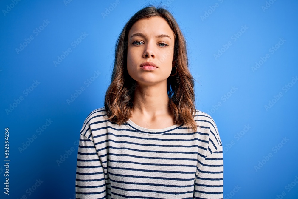 Fototapeta premium Young beautiful blonde girl wearing casual sweater standing over blue isolated background Relaxed with serious expression on face. Simple and natural looking at the camera.