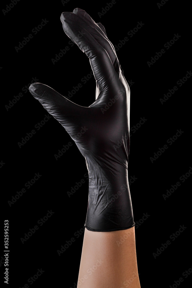 Hand in black gloves holding something with two fingers isolated on black