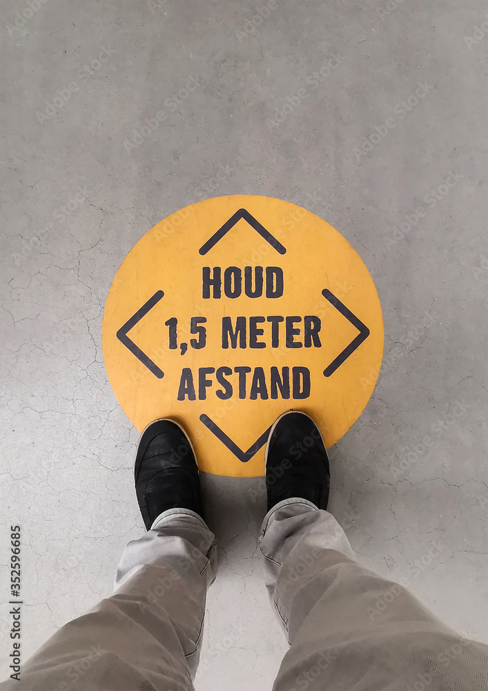A person standing on a social distancing sign. Translation of Dutch text:  “Keep 1.5 meter distance”. Stock Photo | Adobe Stock
