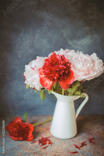 Toned photo. Vase with bouquet of beautiful peonies on table in room, close-up. Bloom. Peony. 