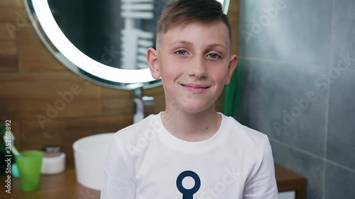 Handsome smiling teenage boywith blue eyes looking at camera in the bathroom photo