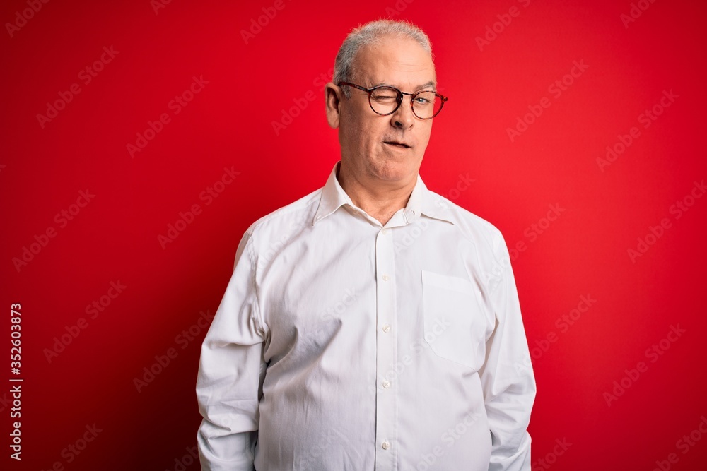 Middle age handsome hoary man wearing casual shirt and glasses over red background winking looking at the camera with sexy expression, cheerful and happy face. Middle age handsome hoary man wearing casual shirt and glasses over red background winking looking at the camera with sexy expression, cheerful and happy face.