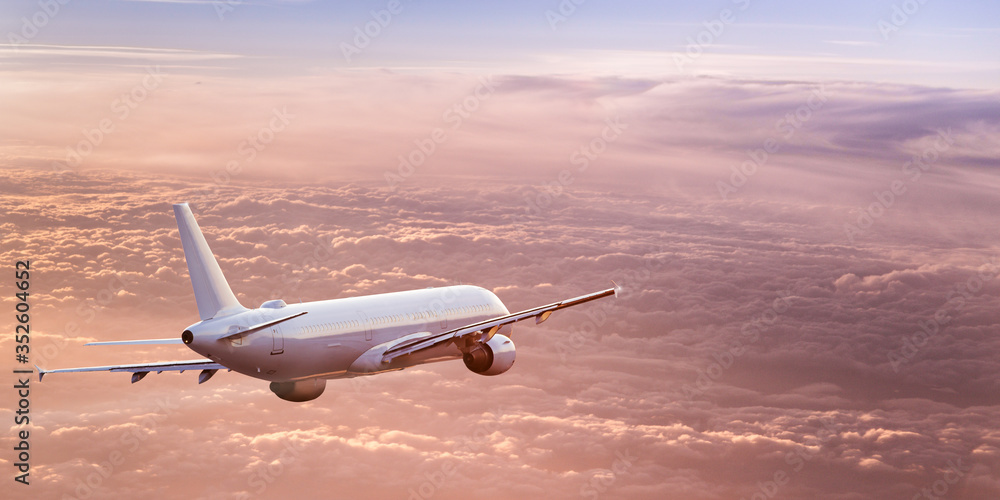 Fototapeta Komercyjny samolot jetliner lecący nad dramatycznymi chmurami w pięknym świetle. Koncepcja podróży.
