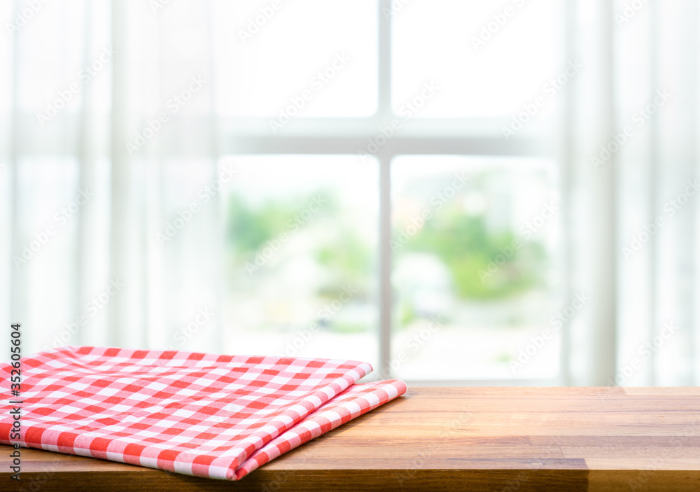 Red fabric,cloth on wood table top on blur window in morning background.For montage product display or design key visual