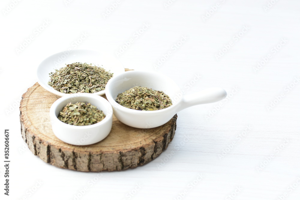Chopped dried leaves of basil leaves on white wooden background Chopped dried leaves of basil leaves on white wooden background
