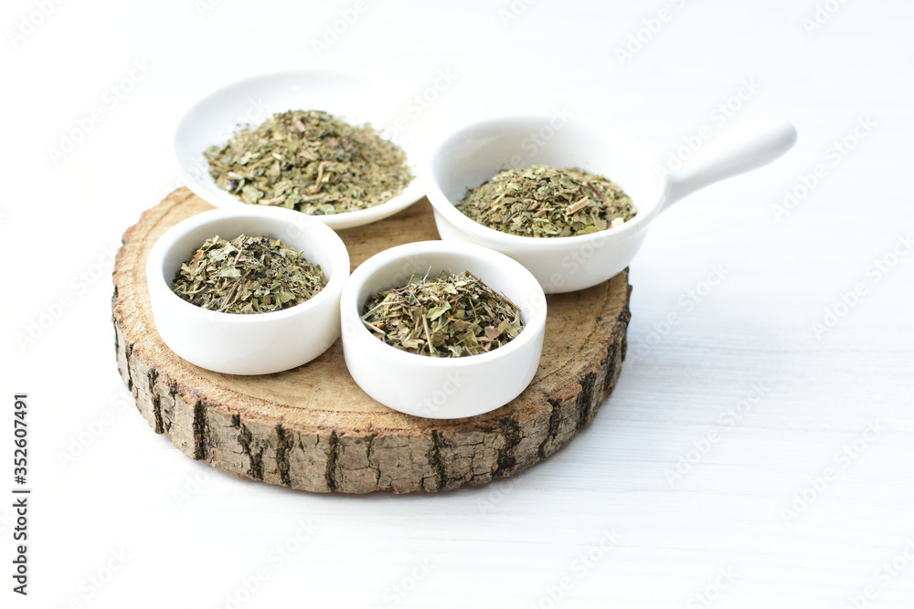 Chopped dried leaves of basil leaves on white wooden background Chopped dried leaves of basil leaves on white wooden background
