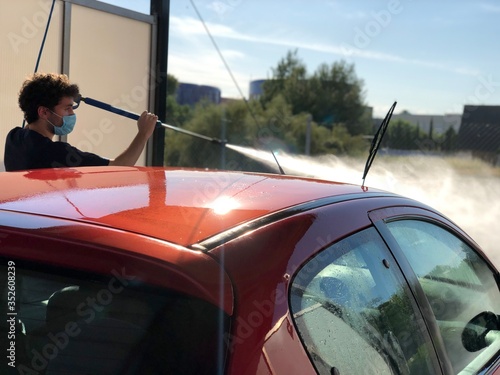 
adult cleaning car with face mask