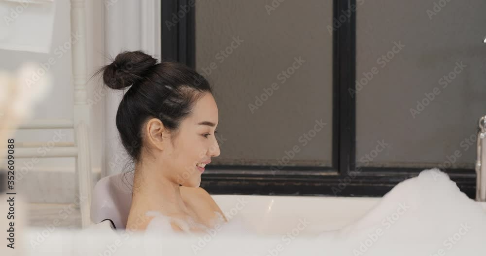 Beautiful asian woman taking a bubble bath in the bathroom. She cleaning herself with happy emotion. Beautiful asian woman taking a bubble bath in the bathroom. She cleaning herself with happy emotion.