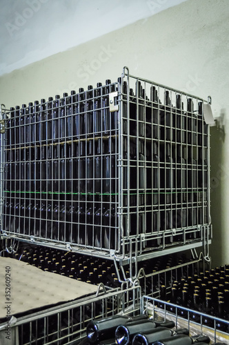 Stacked wine bottles in metal grids before to be labeled - pattern background