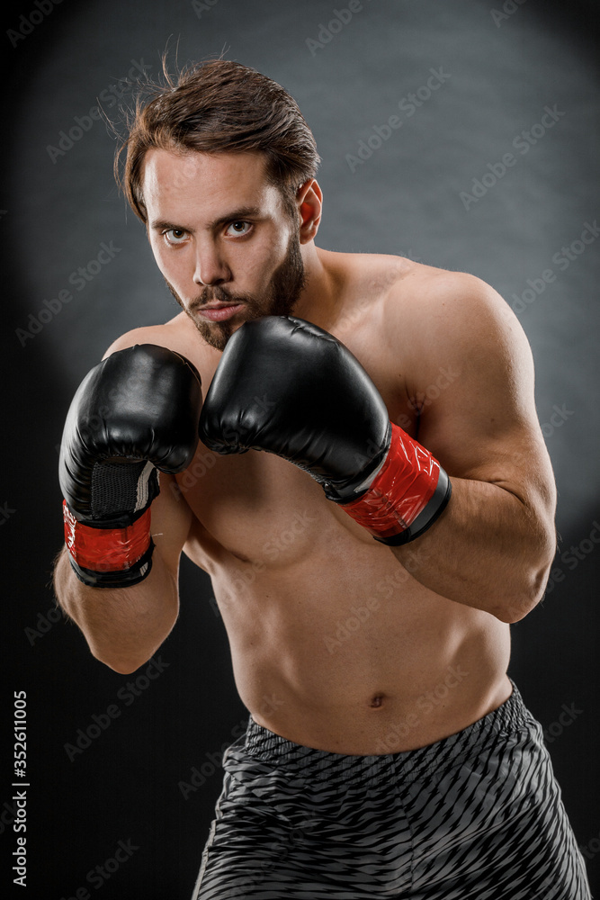 A man in Boxing gloves. A man Boxing on a black background. The concept of a healthy lifestyle