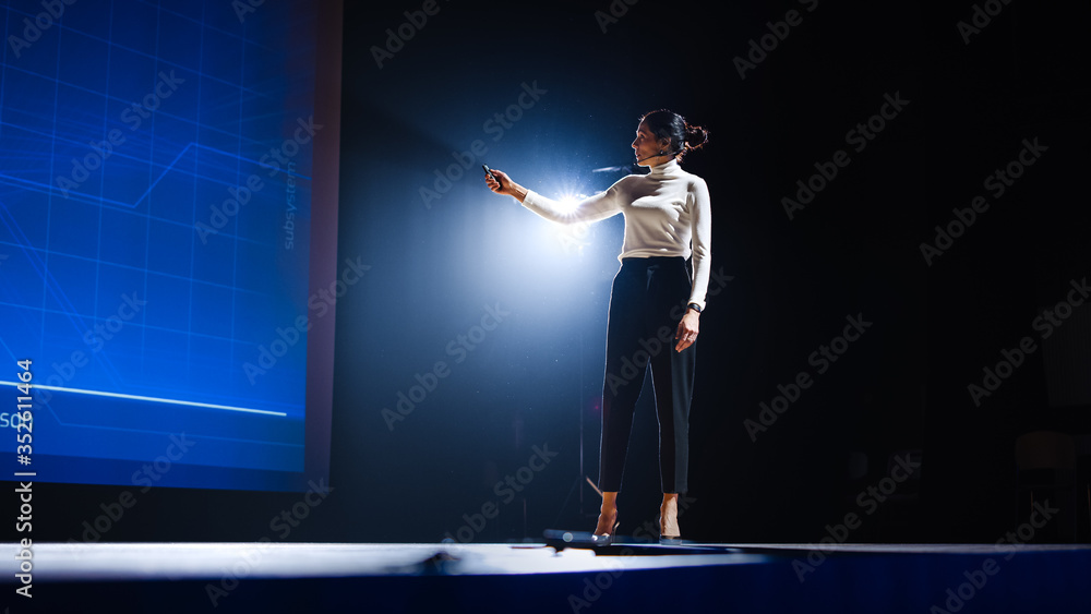 On-Stage Successful Female Speaker Presents Technological Product, Uses  Remote Control for Presentation, Showing Infographics, Statistics Animation  on Screen. Live Event / Device Release. Photos | Adobe Stock