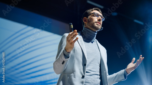 Portrait of Inspirational Innovative Speaker, Talking about Happiness, Self, Success, Empowerment, Efficiency and How to Be More Productive Self. Large Conference Hall with Cinematographic Light photo