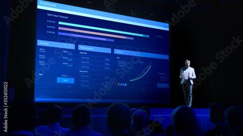 Business Forum Economics Conference Stage: Professional Speaker Concludes His Report with a Speech and Showing Infographics, Statistics on the Big Screen. photo