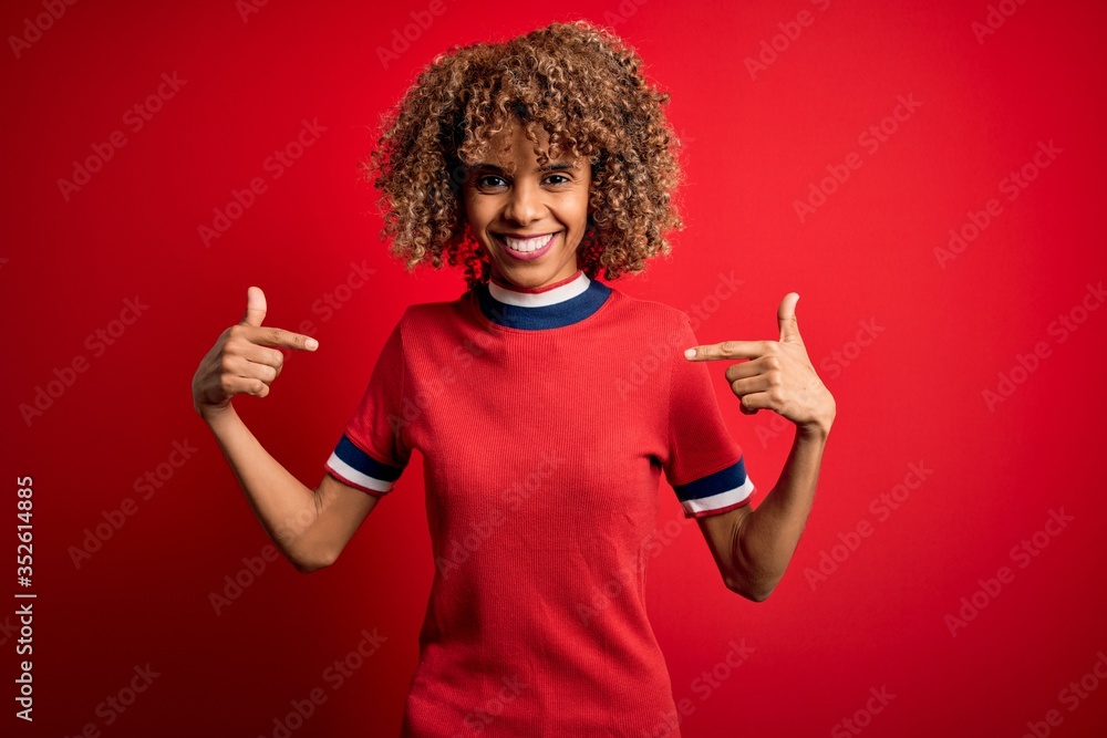 Young beautiful african american woman wearing casual t-shirt standing over red background looking confident with smile on face, pointing oneself with fingers proud and happy. Young beautiful african american woman wearing casual t-shirt standing over red background looking confident with smile on face, pointing oneself with fingers proud and happy.