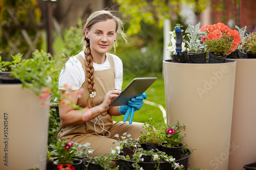 The gardener checks the condition and availability of flowers, checks with the entries in the tablet. Modern technologies, business