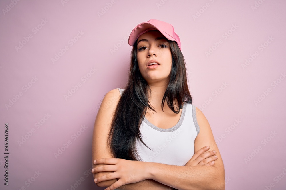 Young brunette woman wearing casual sport cap over pink background Relaxed with serious expression on face. Simple and natural looking at the camera. Young brunette woman wearing casual sport cap over pink background Relaxed with serious expression on face. Simple and natural looking at the camera.
