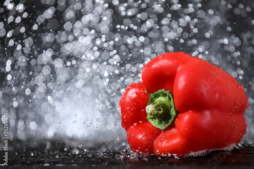 Horizontal view of red sweet paprika under the water drops in a black background. Healthy lifestyle.