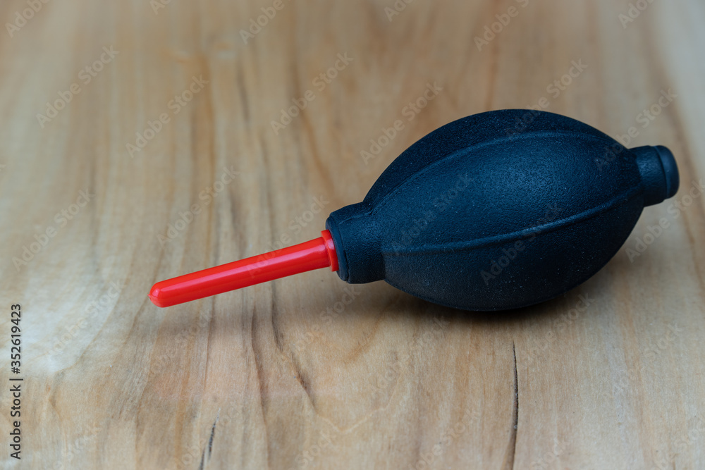 Camera cleaning kit, black and red pump on a wooden table. Camera cleaning kit, black and red pump on a wooden table.