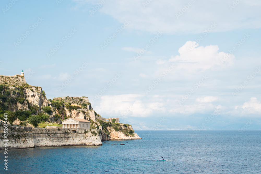 Europe Greece Corfu travel vacation.Panoramic view of Kerkyra, capital of Corfu island, Greece. Amazing view of sea and mountain cliff with old historical architecture buildings in sunny day.