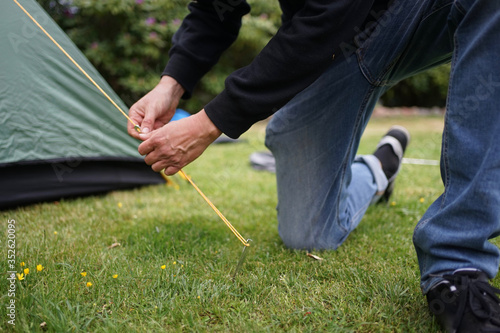 Close up of a man setting up a tent for camping 