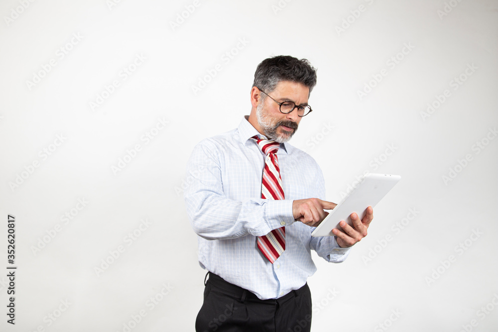 Surprised man in suit reading and typing on his tablet on white studio background Surprised man in suit reading and typing on his tablet on white studio background