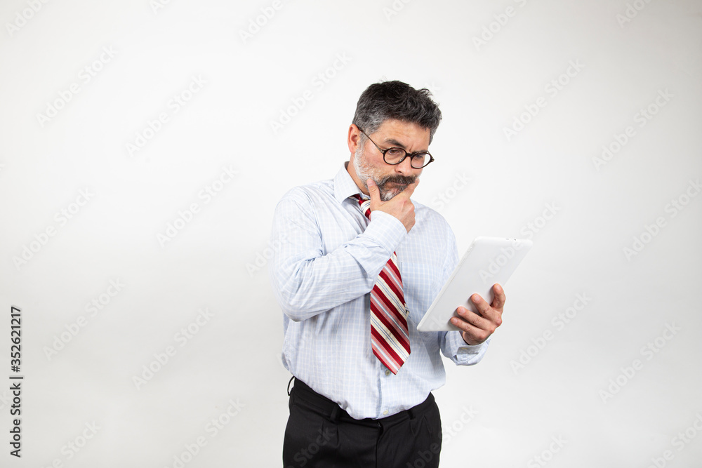 Portrait of classy serious Caucasian businessman in suit and glasses using tablet to read news on white background. Portrait of classy serious Caucasian businessman in suit and glasses using tablet to read news on white background.