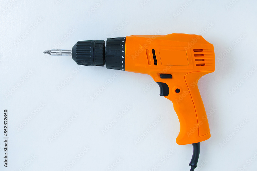 Close-up electric orange drill screwdriver on white background. View from above.