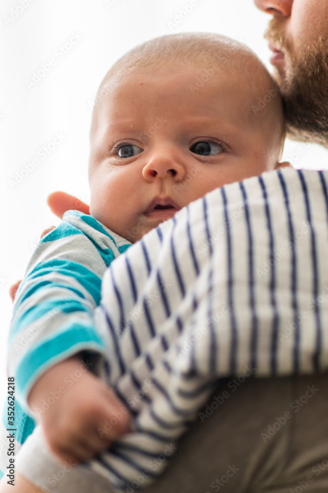 Little baby boy burps and spits on the fabric diaper in the arms of his daddy. Baby with reflux held by his father.