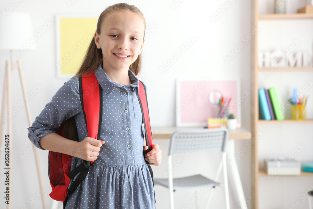 Lovely schoolgirl with a backpack in the interior of a bright room