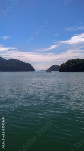 View of beautiful mountains and blue sky during a relaxing afternoon over the calm sea on a boat in Phang Nga Island, Thailand.