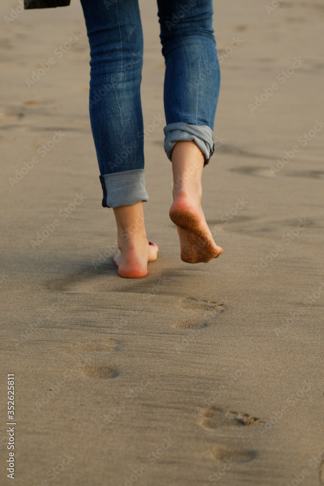 young woman walking on the beach, footprints in the sand, space for text, vacation for relaxing time, 