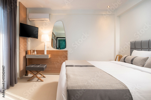 Side view of light gray and wooden bedroom interior in modern style hotel apartment room with empty wall copy space