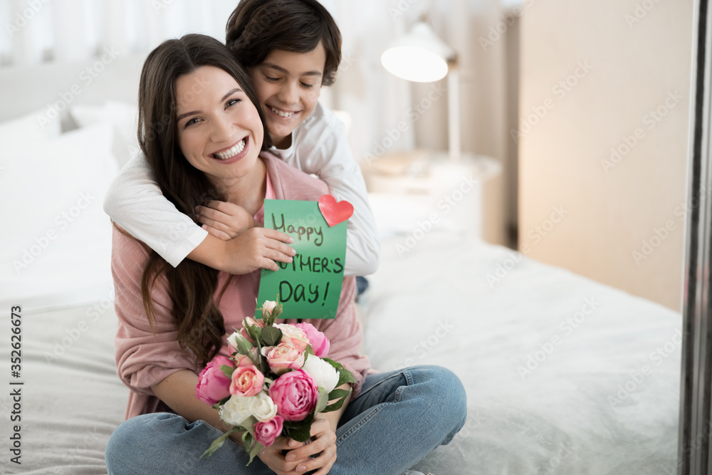 High-spirited woman with flowers sitting on the bed High-spirited woman with flowers sitting on the bed