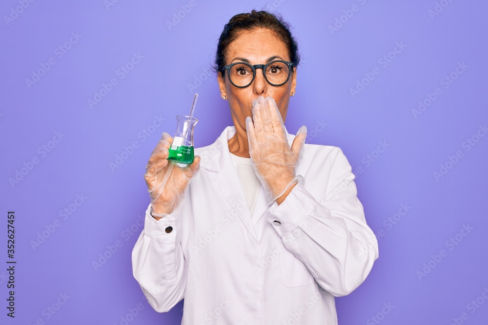 Middle age senior scientist woman wearing laboratory coat holding research test tube cover mouth with hand shocked with shame for mistake, expression of fear, scared in silence, secret concept Middle age senior scientist woman wearing laboratory coat holding research test tube cover mouth with hand shocked with shame for mistake, expression of fear, scared in silence, secret concept