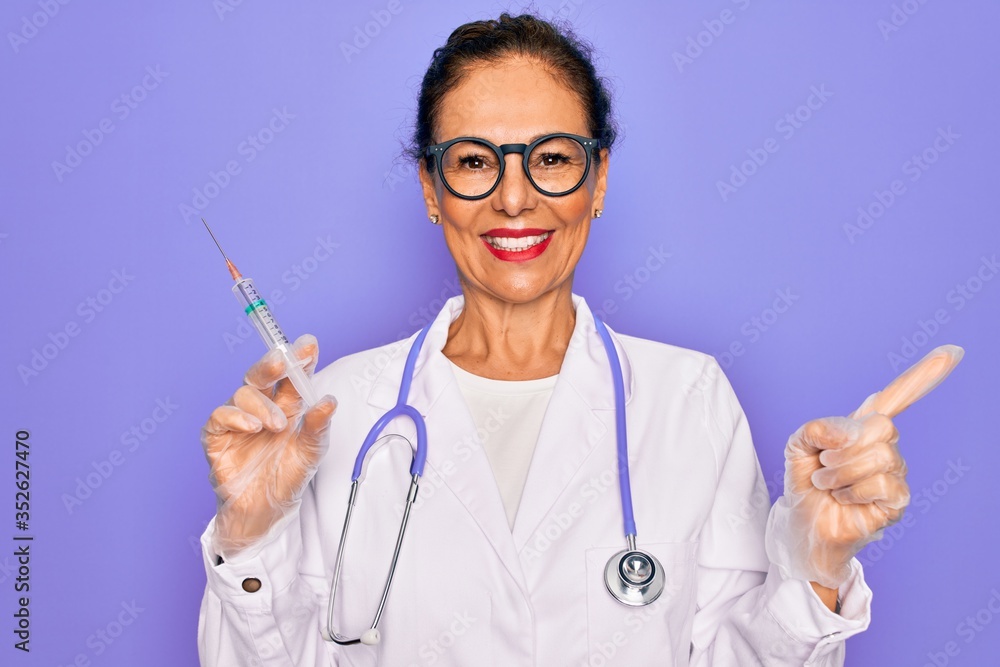 Middle age senior professional doctor woman holding syringe with medical vaccine very happy pointing with hand and finger to the side Middle age senior professional doctor woman holding syringe with medical vaccine very happy pointing with hand and finger to the side