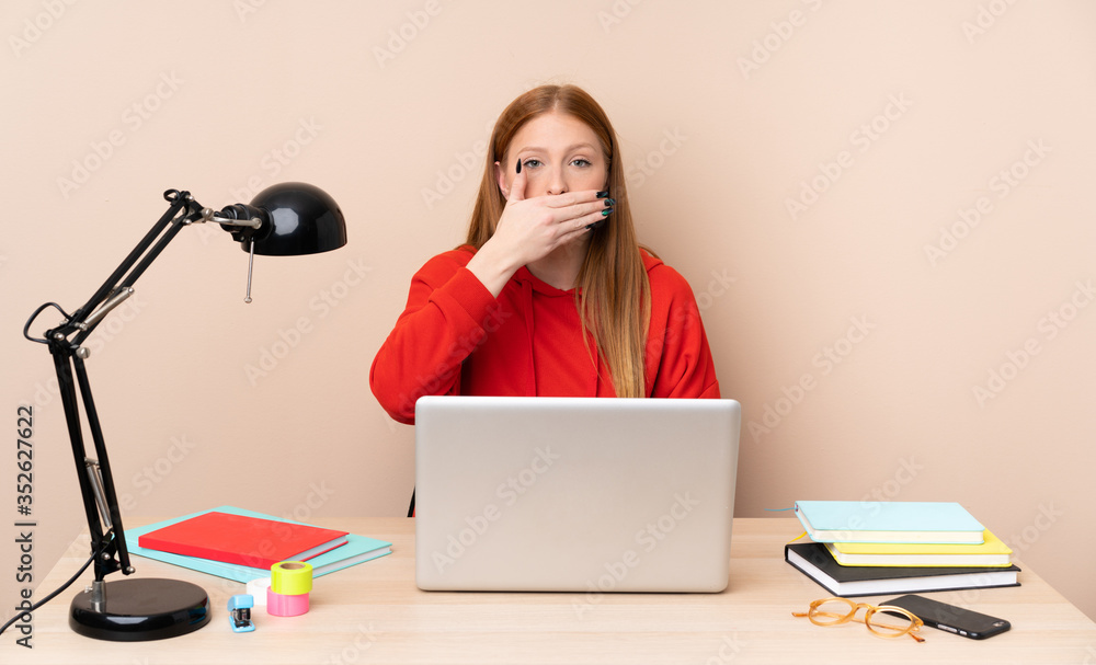 Young student woman in a workplace with a laptop covering mouth with hands Young student woman in a workplace with a laptop covering mouth with hands