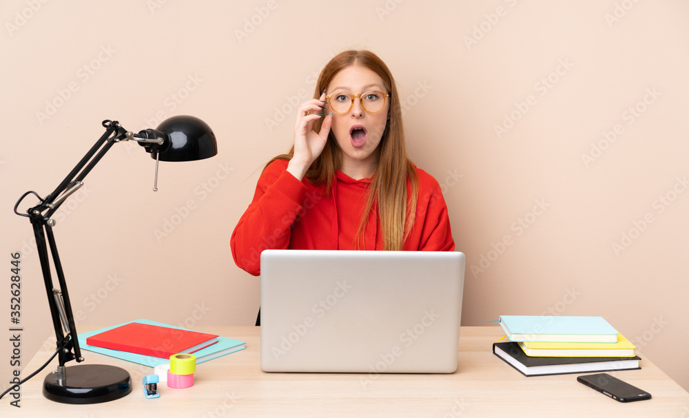 Young student woman in a workplace with a laptop with glasses and surprised Young student woman in a workplace with a laptop with glasses and surprised